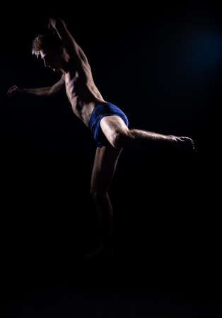 Studio fashion portrait of a handsome shirtless guy isolated on black backgorundの写真素材