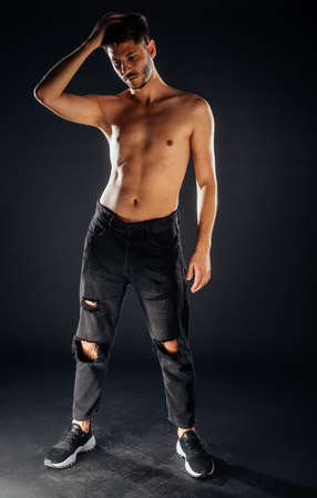Trendy shirtless man posing in black pants and sport shoesの写真素材