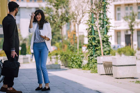 Two business people in an informal conversation in front of a business buildingの写真素材