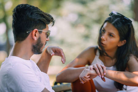 Couple of young lovers sitting close on wooden bench in park on a dateの写真素材