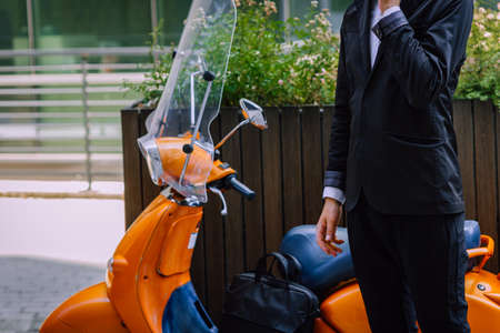 Corporate executive while talking on his phone and looking at his  bikeの写真素材