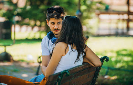 Young loving couple of tourist sitting in the park bench and having fun