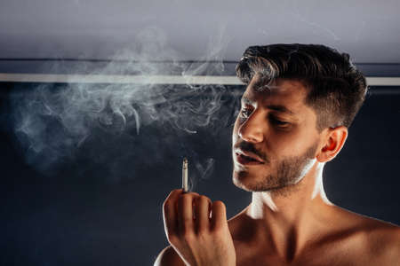 Portrait of a handsome stylish man posing topless against black background