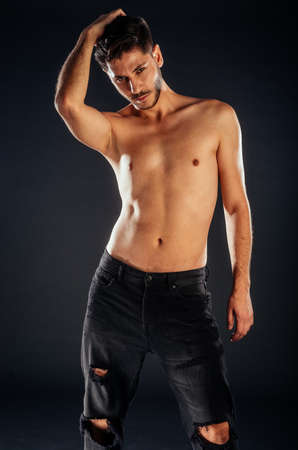 Stylish fashion guy posing topless against dark backgroundの写真素材