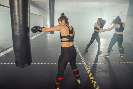 Two young women boxing in the gym. They are wearing black sportswear.の写真素材