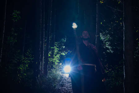 Portrait of young mysterious wizard having fun into the woods