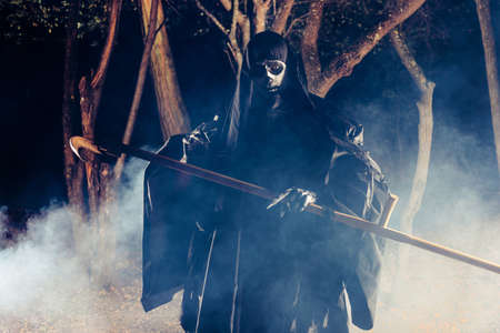 Grim Reaper standing in the fog at night with his scythe.
