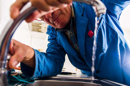 Professional male serviceman is fixing the kitchen faucetの写真素材