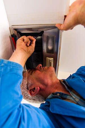 Senior handyman fixing the household appliances in apartment