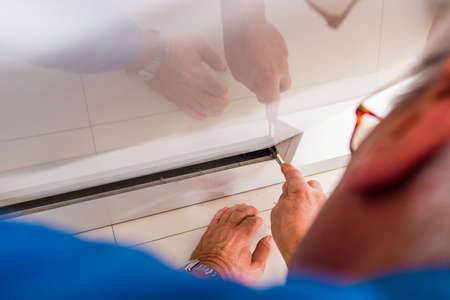 Plumber is opening the kitchen dishwasher with toolsの写真素材