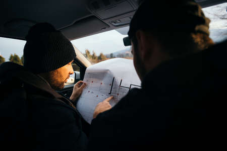 Two robbers planning and pointing on the blueprint(map) their objective while holding their guns.の写真素材