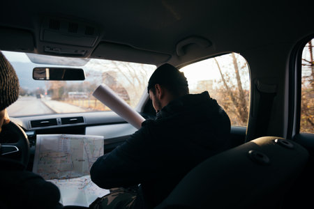 Two violent robbers sitting in a car looking at a blueprint of the building they want to rob while proudly showing off their guns.の写真素材