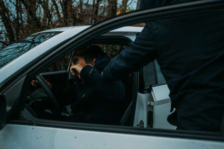 Gangster with a gun trying to rob a guy which is sitting in his car.の写真素材