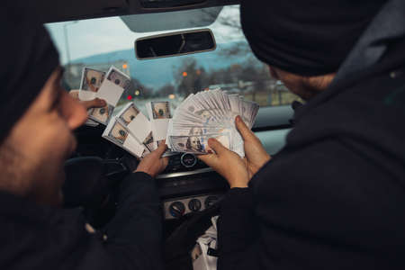 Two happy bank robbers celebrating their successful hit while sitting in the car they used for the robbery.の写真素材