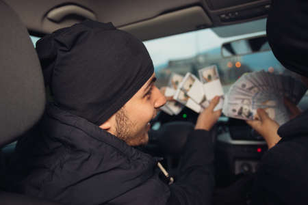 Two happy bank robbers celebrating their successful hit while sitting in the car they used for the robbery.の写真素材