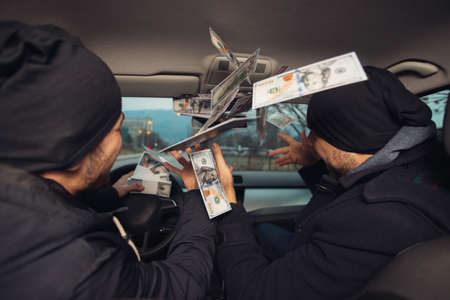 Two happy bank robbers celebrating their successful hit while sitting in the car they used for the robbery.の写真素材
