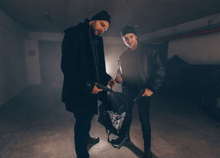 Assaulters standing in a dark room with guns and stolen money