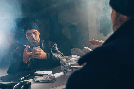 Gangsters are counting money in a smoky room