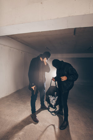 Masked men are holding guns and bag full of stolen moneyの写真素材