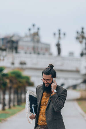Modern day hipster making a business phone call at the city river