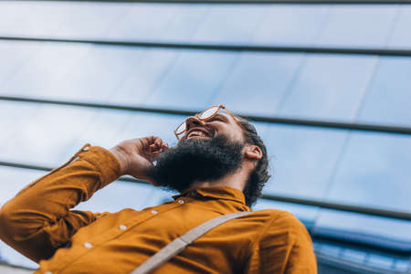 Stylish hipster with a long beard during a business phone conversation