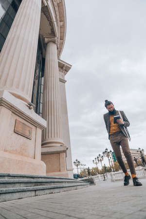 Stylish caucasian male clothed in a fashionable outfit walking outdoors