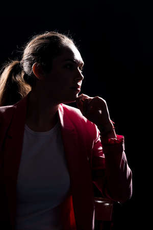 Stylish fashion girl posing while sitting on cheir in modern studioの写真素材