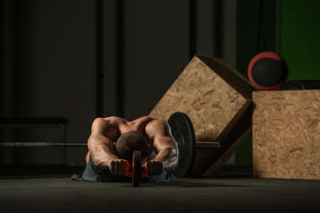 Shirtless pro athlete doing russian twist abs workout. Close up photo of a fit male athlete doing indoor training.の写真素材