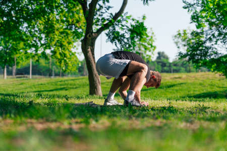 Sporty young man practicing crow pose or bakasana, yoga asana, outdoors in a park