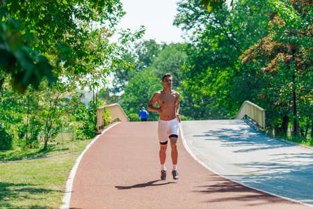 A strong attractive man running shirtless outside in the parkの写真素材