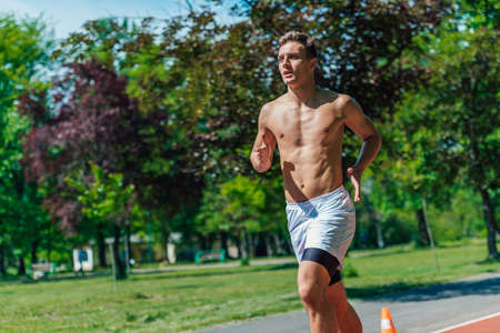 A strong attractive man running shirtless outside in the parkの写真素材