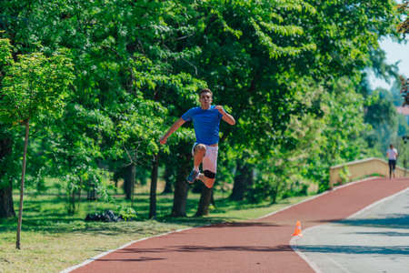 Caucasian young male runner in sportswear jumping in the parkの写真素材