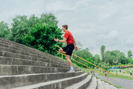 Fit male athlete performing stairs workout, running up climbing stairs performing outdoor track cardio.の写真素材