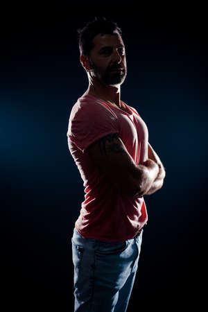 Attractive fashion model wearing blue jeans and red t-shirt posing in modern studio