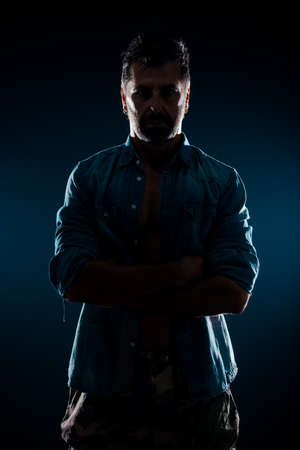 Cool shirtless guy wearing stylish unbuttoned blue shirt over naked torsoの写真素材