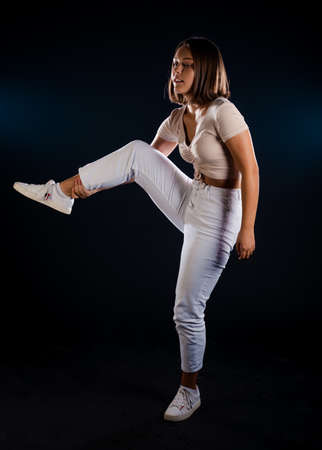 Beautiful young and fit fitness sport model doing stretching in dark studioの写真素材