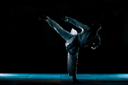 Young man practicing his karate moves, white kimono and black belt