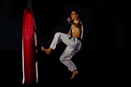 The fighter of mixed martial arts beats the bag with his left foot on the sideの写真素材