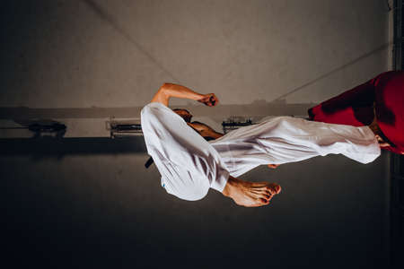 Handsome shirtless boxer training with punching bag on black backgroundの写真素材