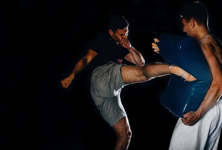 Portrait of a young athlete handsome sports man boxing red bag. Practicing boxing on a punching bag...