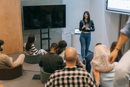 Young woman giving a business lecture to a diverse group of employeesの写真素材