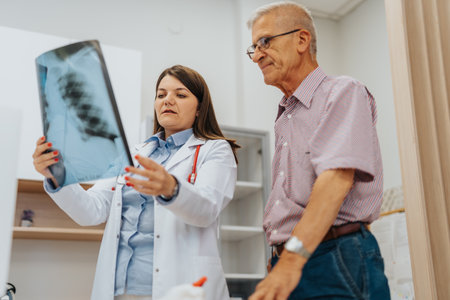 Doctor carefully examines x-ray film of elderly patients lungs in office. Expert consultation for...