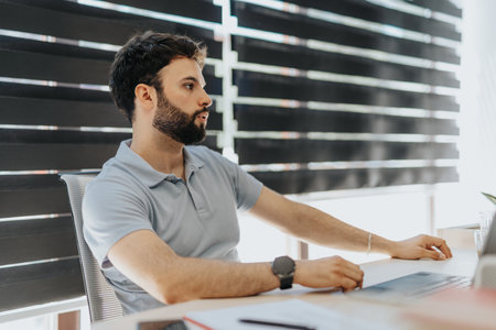 Handsome male employee carefully listening to his project team leader in meeting.