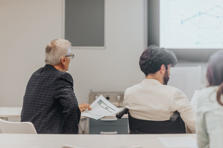 Back view photo of mature business person listening to a presentation at the classroom, he is...