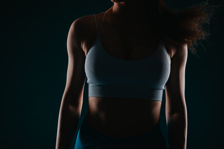 Fit Girl Posing with Confidence in Dark Backgroundの写真素材