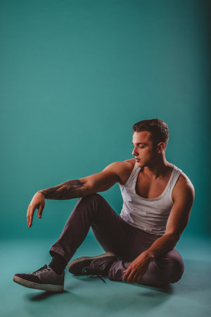 Confident Male Athlete Posing to Showcase Muscular Progress on Turquoise Backgroundの写真素材