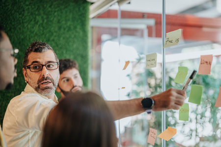 Collaborative Business Group Brainstorming in Glass-Enclosed Officeの写真素材