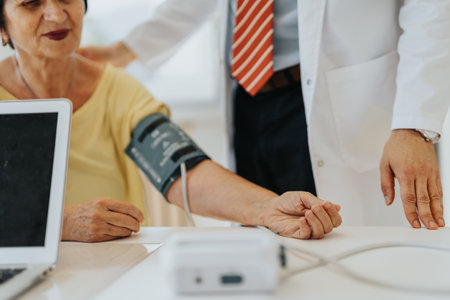 A cardiologist carefully examines an elderly patients health, measuring blood pressure and monitoring heart rate in a well-equipped medical office.の写真素材
