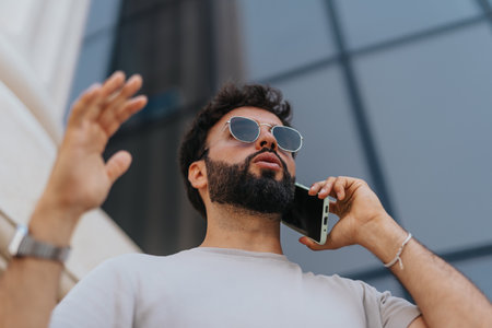 Low angle view of businessman negotiating with client on phone outdoors.の写真素材