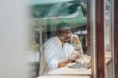 Male broker having phone call at work. Shot through window.の写真素材